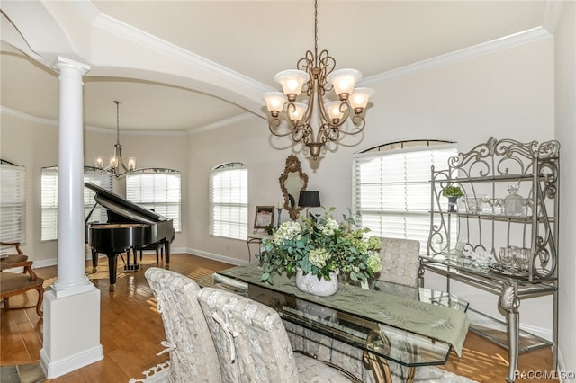 dining room featuring decorative columns, crown molding, wood-type flooring, and a notable chandelier