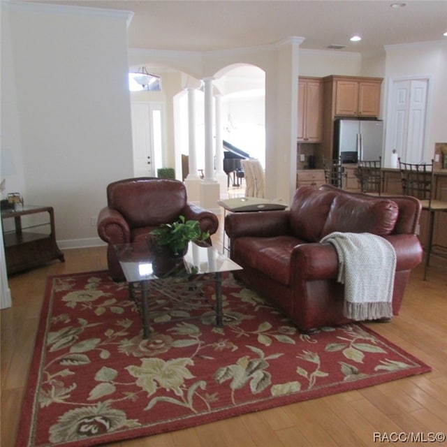 living room with ornamental molding, decorative columns, and light wood-type flooring