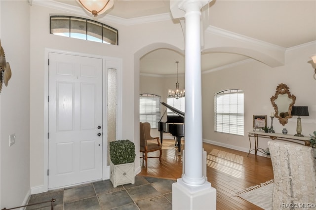 foyer entrance with decorative columns, ornamental molding, a wealth of natural light, and a notable chandelier