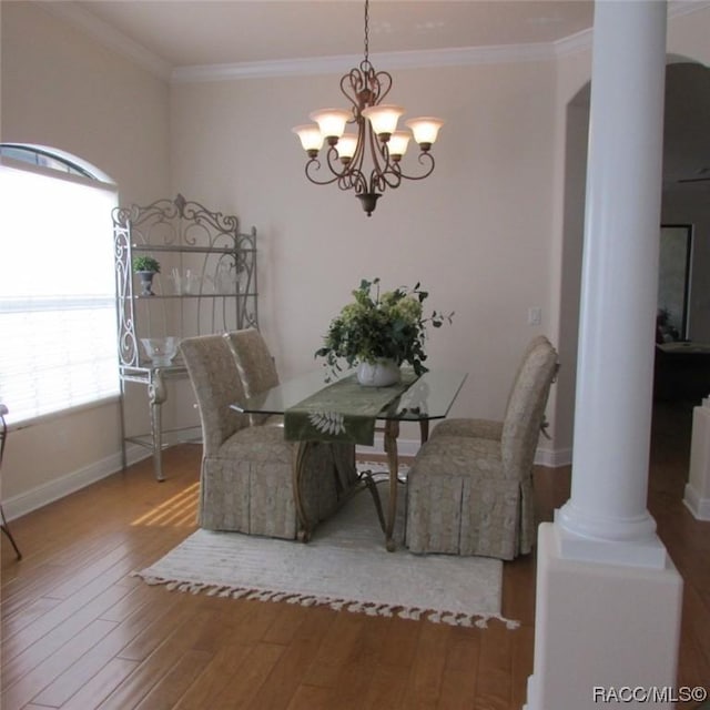 dining room with hardwood / wood-style flooring, ornamental molding, decorative columns, and a chandelier