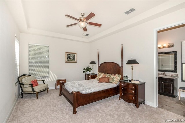 carpeted bedroom featuring ceiling fan, ensuite bathroom, a tray ceiling, and sink