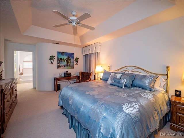 carpeted bedroom featuring ceiling fan, connected bathroom, and a tray ceiling