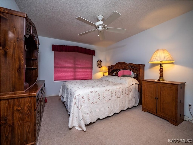 bedroom featuring ceiling fan, light colored carpet, and a textured ceiling