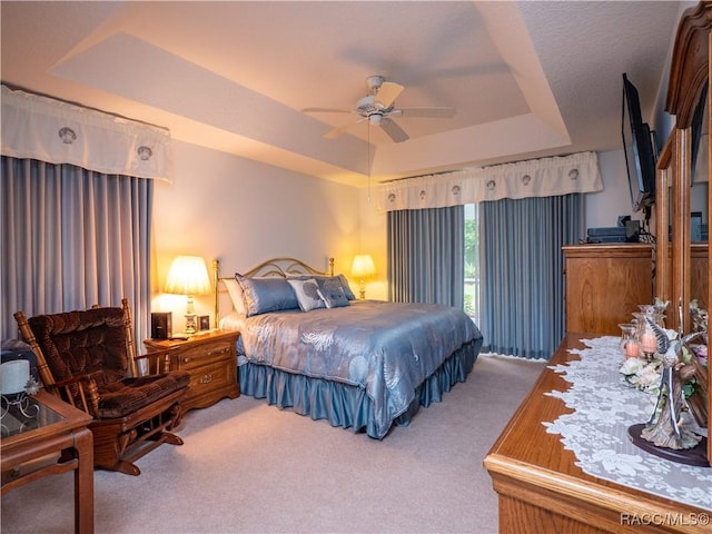 bedroom with ceiling fan, carpet, and a tray ceiling