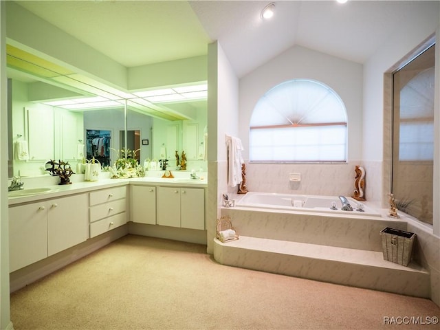 bathroom featuring vaulted ceiling, tiled tub, and vanity