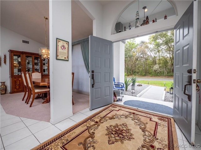 entryway featuring a notable chandelier, light tile patterned floors, and lofted ceiling