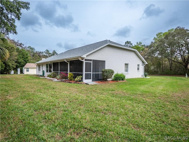 back of property featuring a sunroom and a lawn