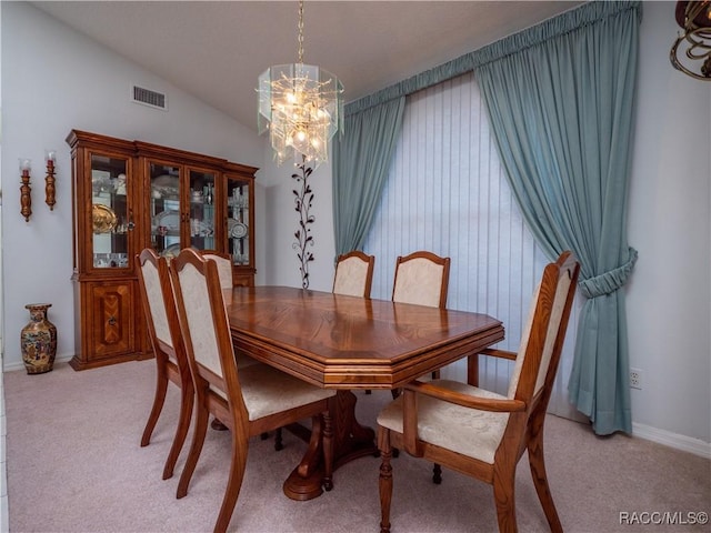 dining space with light colored carpet, vaulted ceiling, and a notable chandelier