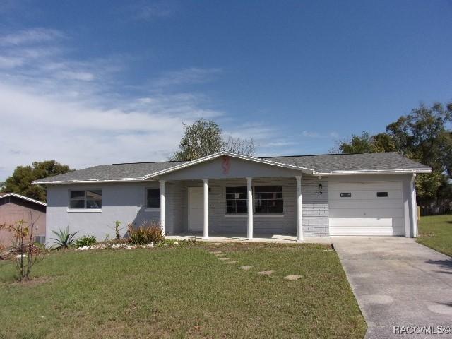 ranch-style house featuring a garage, driveway, a porch, and a front yard