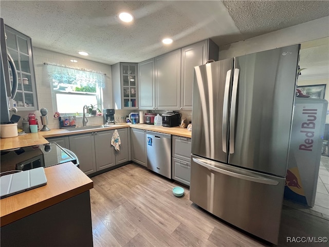 kitchen with gray cabinetry, light hardwood / wood-style flooring, a textured ceiling, butcher block countertops, and stainless steel appliances