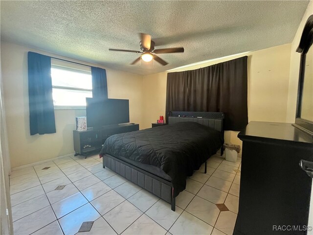 tiled bedroom with ceiling fan and a textured ceiling