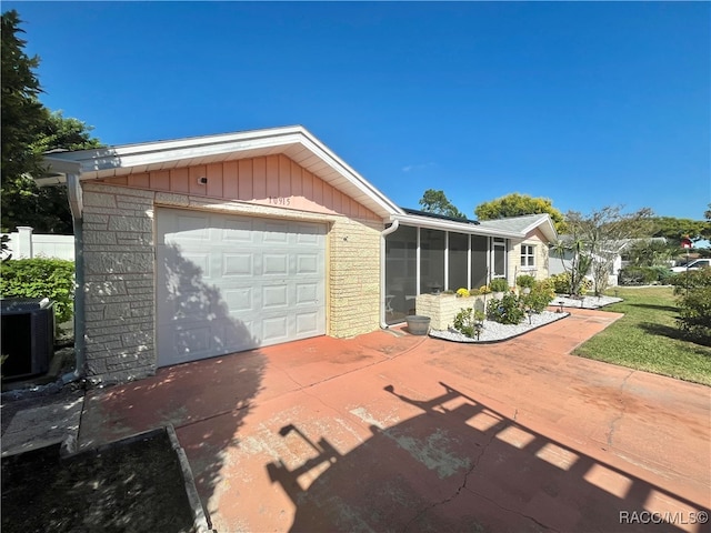 view of front of home with a sunroom, a garage, and central AC