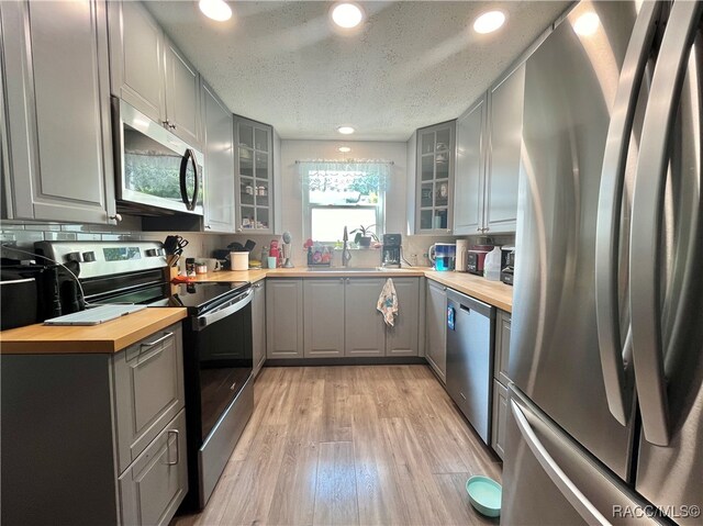 kitchen with butcher block countertops, gray cabinetry, a textured ceiling, and appliances with stainless steel finishes