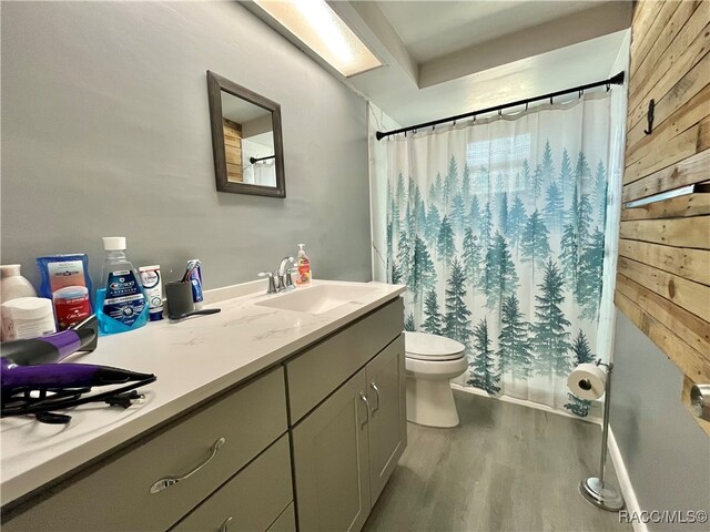 bathroom featuring wooden walls, toilet, vanity, and hardwood / wood-style flooring