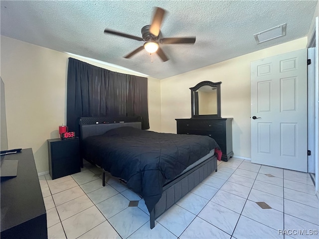 bedroom featuring ceiling fan, light tile patterned floors, and a textured ceiling