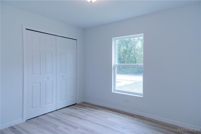 97 W Camino Ln, Citrus Springs, FL 34434 - unfurnished bedroom with light wood-style floors, baseboards, and a closet