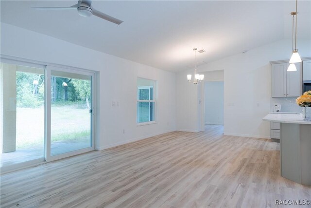 97 W Camino Ln, Citrus Springs, FL 34434 - unfurnished living room featuring light wood-type flooring, baseboards, ceiling fan with notable chandelier, and lofted ceiling