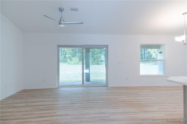 97 W Camino Ln, Citrus Springs, FL 34434 - empty room with ceiling fan with notable chandelier, light wood-style flooring, and a wealth of natural light