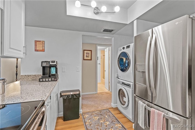 688 Midway Dr Unit B, Ocala, FL 34472 - kitchen with stainless steel appliances, stacked washer / drying machine, white cabinetry, light stone counters, and light wood-type flooring