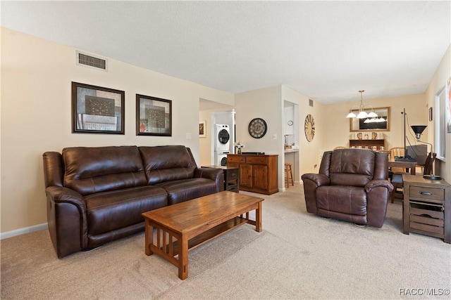 688 Midway Dr Unit B, Ocala, FL 34472 - living room with stacked washer / dryer, light colored carpet, a chandelier, and baseboards