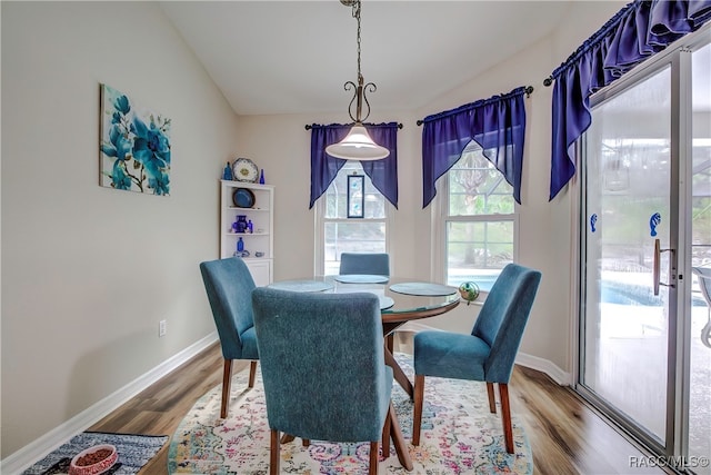 dining space featuring vaulted ceiling and wood-type flooring