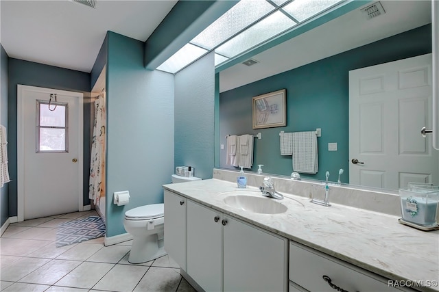 bathroom with toilet, tile patterned floors, a skylight, and vanity