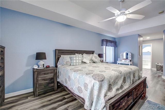 bedroom with a tray ceiling, hardwood / wood-style floors, and ceiling fan