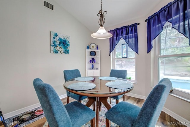 dining space featuring vaulted ceiling and wood-type flooring