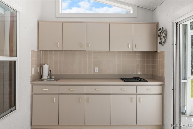 kitchen with backsplash, vaulted ceiling, and sink