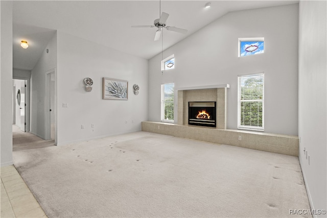 unfurnished living room with ceiling fan, light colored carpet, high vaulted ceiling, and a tiled fireplace