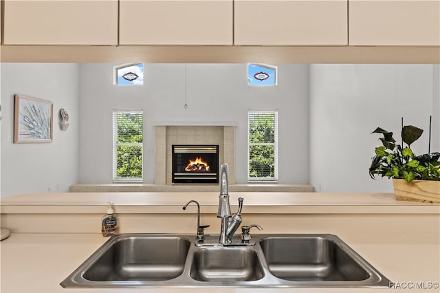 kitchen with a tiled fireplace, sink, and a healthy amount of sunlight