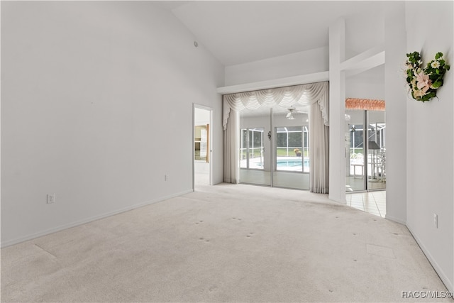 carpeted empty room with high vaulted ceiling