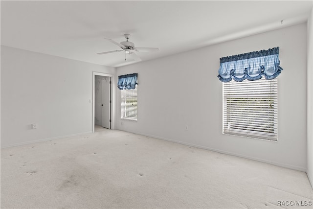 carpeted spare room featuring ceiling fan and a healthy amount of sunlight