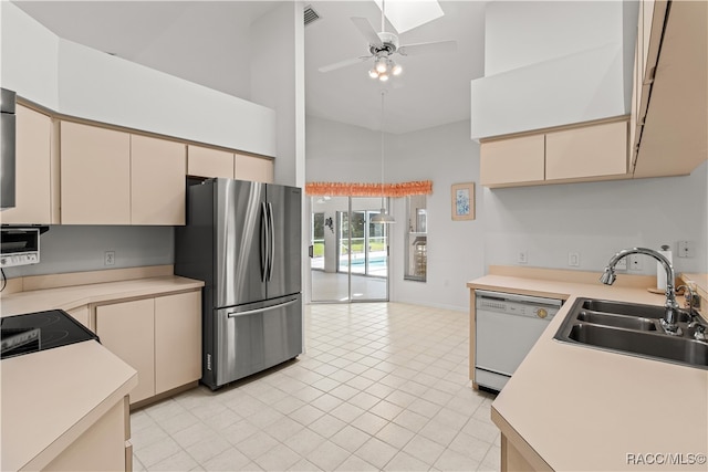 kitchen with white dishwasher, sink, cream cabinets, high vaulted ceiling, and stainless steel refrigerator