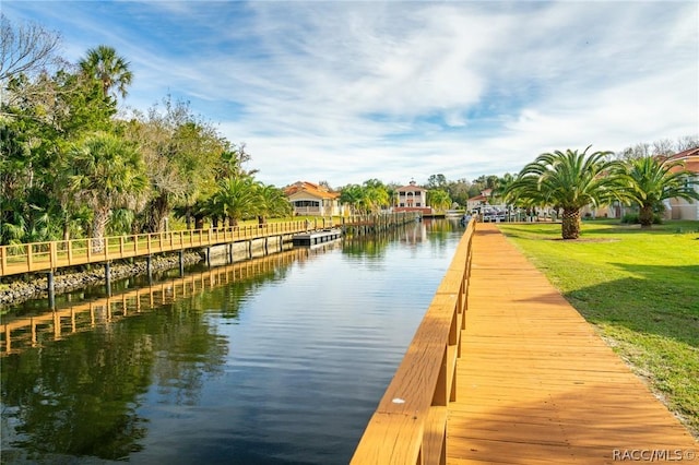 view of dock with a yard and a water view