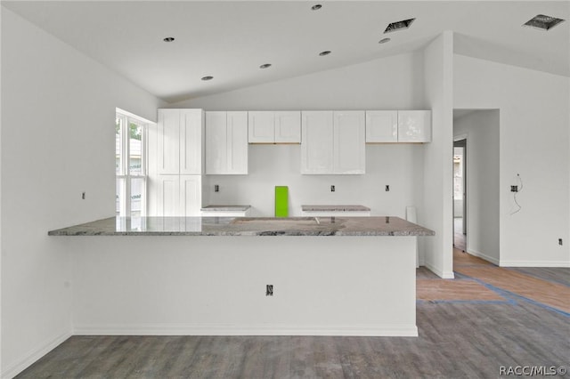 kitchen featuring kitchen peninsula, wood-type flooring, lofted ceiling, stone countertops, and white cabinets