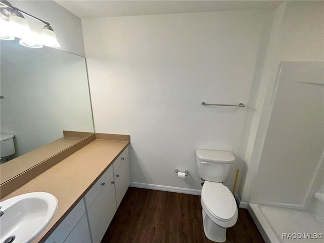 full bath with a shower, toilet, vanity, wood finished floors, and baseboards