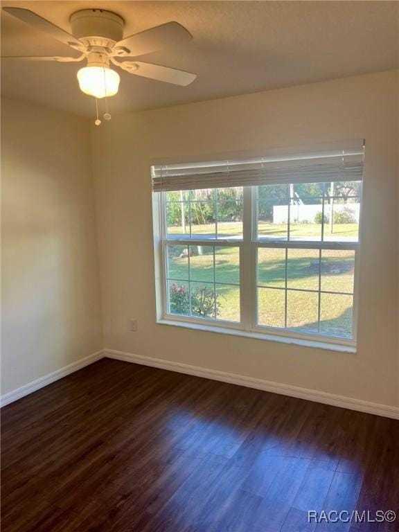 spare room featuring a ceiling fan, dark wood finished floors, and baseboards