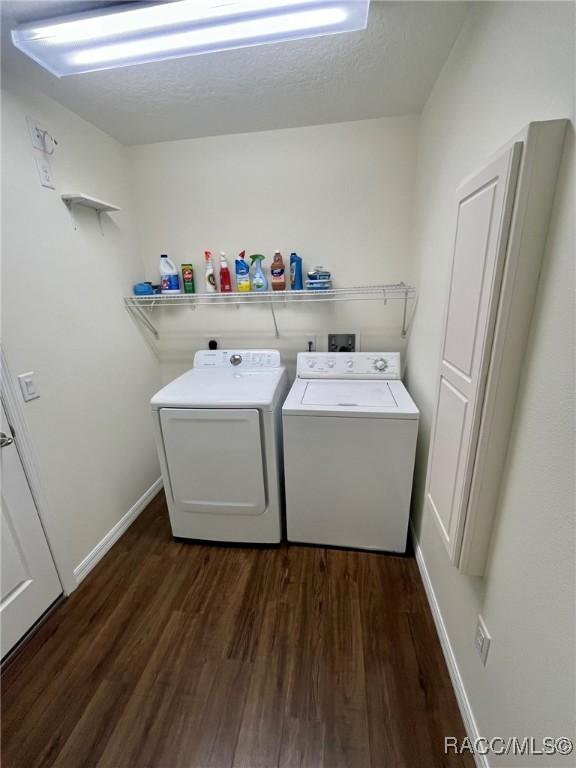 laundry area featuring dark wood-style flooring, washing machine and clothes dryer, a textured ceiling, laundry area, and baseboards