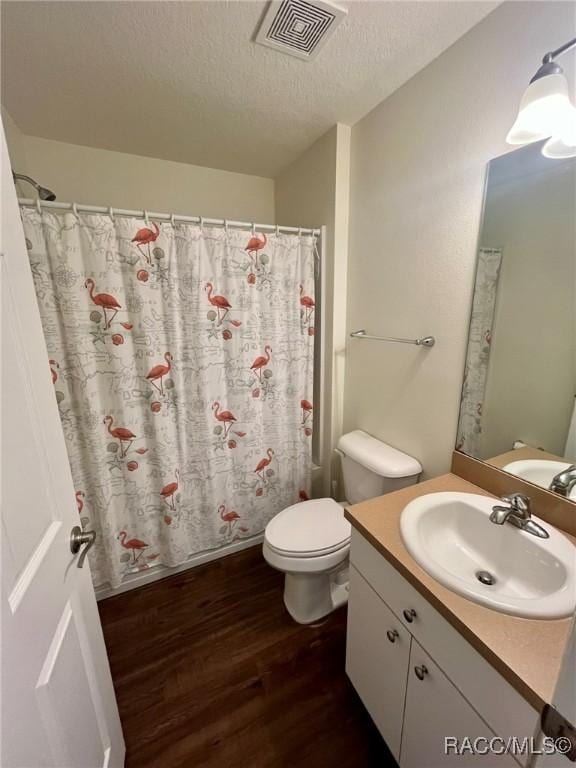 bathroom with visible vents, toilet, a textured ceiling, vanity, and wood finished floors