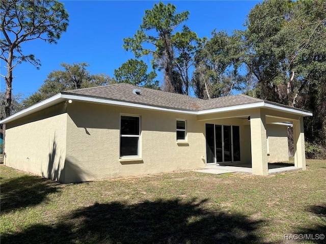 rear view of house with a lawn and stucco siding