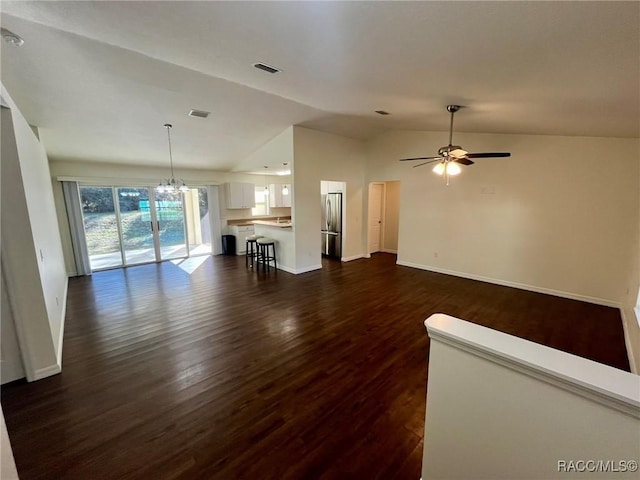 unfurnished living room featuring lofted ceiling, visible vents, dark wood finished floors, and ceiling fan with notable chandelier