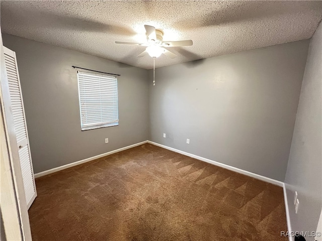 empty room with dark colored carpet, a textured ceiling, and ceiling fan