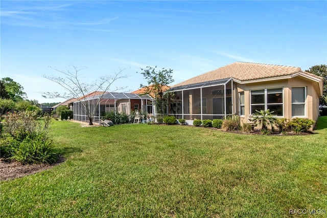 rear view of house featuring a lawn and glass enclosure