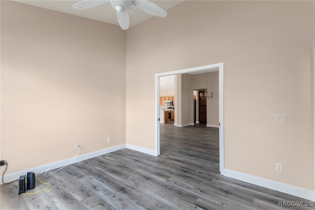 unfurnished room featuring a towering ceiling, hardwood / wood-style flooring, and ceiling fan