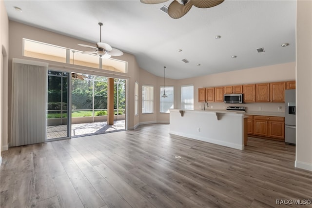 kitchen featuring a kitchen bar, stainless steel appliances, light hardwood / wood-style flooring, and a center island with sink