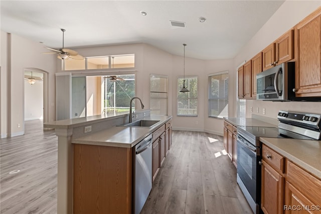 kitchen featuring sink, vaulted ceiling, ceiling fan, light wood-type flooring, and stainless steel appliances