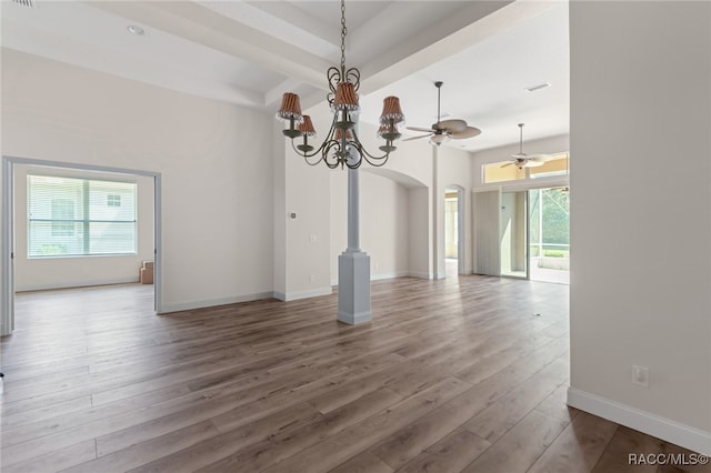 unfurnished dining area with wood-type flooring and ceiling fan with notable chandelier