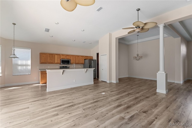 kitchen with stainless steel appliances, ceiling fan, decorative light fixtures, a center island, and light hardwood / wood-style floors