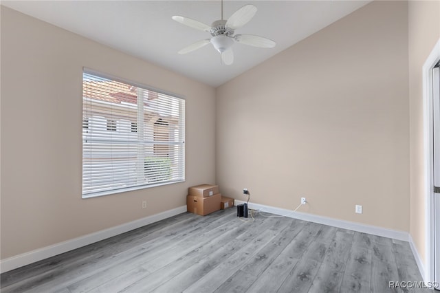 empty room featuring ceiling fan, a healthy amount of sunlight, vaulted ceiling, and light wood-type flooring